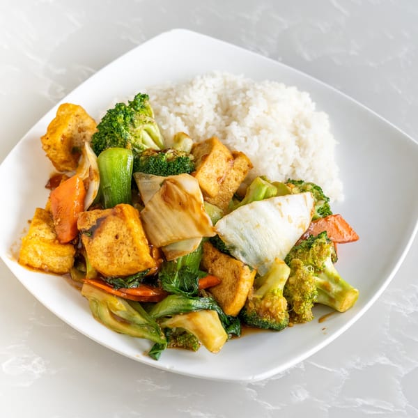 Asian-fusion stir-fry with tofu, broccoli, carrots, and bok choy, served with white rice.