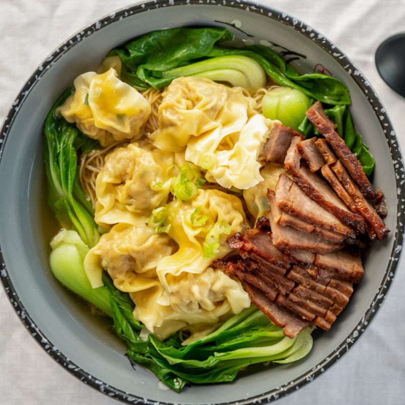 A bowl of Sharetea Fatty Panda's wonton noodle soup with sliced char siu pork and bok choy.